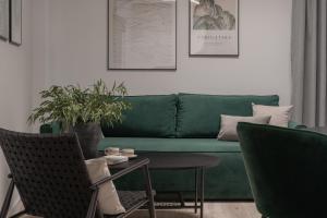 a living room with a green couch and a table at Harbor Apartments - Aparthotel przy Rynku in Katowice