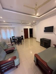 a living room with a couch and a dining room at Sathya HS-2 Bedroom Family Apartments with Balcony in Guruvāyūr
