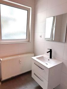 a white bathroom with a sink and a window at Große möblierte Wohnung im Zentrum von Lage in Lage
