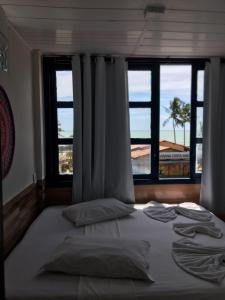 a bed in a room with two windows at Pousada Recanto do Hibisco in Prado