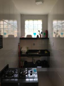 a kitchen with a stove and a sink and a window at Pousada Recanto do Hibisco in Prado