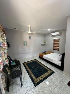 ein Schlafzimmer mit einem Bett, einem Stuhl und einem Tisch in der Unterkunft Soyak Senja Roomstay in Langkawi Intl