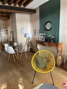 a living room with a yellow chair and a table at La Maison aux volets bleus 37 m3, Bords de Saône in Chalon-sur-Saône