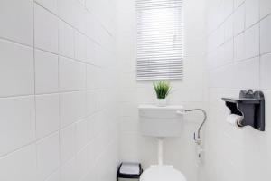 a white bathroom with a toilet with a plant on it at Spacious Valkyrie One-bedroom in Centurion +3 photos