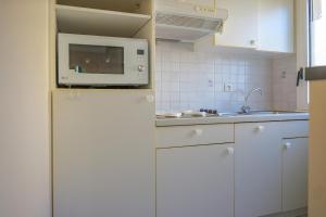 a white kitchen with a microwave on top of a refrigerator at Appartement cœur de ville avec balcon - 3 personnes in Les Sables-dʼOlonne +3 photos