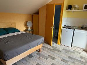 een slaapkamer met een bed en een kleine keuken bij Les Logis du Haut-Folin in Arleuf