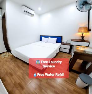 a hotel room with a bed and a desk and a sign that says free laundry at Cat Ba Charm Island Hotel in Cat Ba