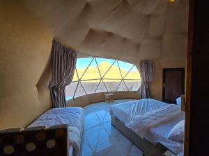 a bedroom with two beds and a large window at Talira Luxury Camp in Wadi Rum