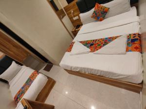 two beds in a room with white sheets and colorful pillows at Hotel Amber Sun City in Mumbai
