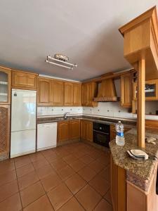 a kitchen with wooden cabinets and a white refrigerator at La Esquina Mayor in Caravaca de la Cruz