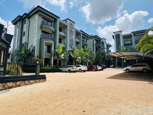 a parking lot with cars parked in front of buildings at Bellwether Apartments in Kampala