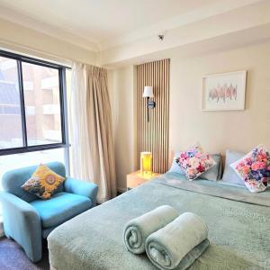 Un dormitorio con una cama grande y una silla azul. en Joyful Stay Stylish Retreat in Perth City, en Perth