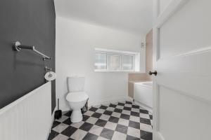 a bathroom with a toilet and a black and white checkered floor at Convenient 2BR House with Free Street Parking in Middleton