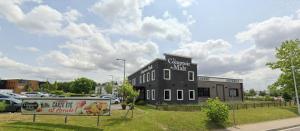 un edificio negro con un cartel en el costado en ibis budget Rouen Nord Isneauville, en Isneauville