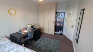 a bedroom with a desk and a bed and a clock at Cosy Double Private Room Near Dublin Airport in Swords +1 photo
