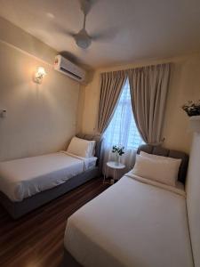 a hotel room with two beds and a window at Homestay Putrajaya Ayer 8 Elzahra Suites With Wi Fi in Putrajaya +51 photos