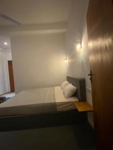 una pequeña habitación blanca con una cama y dos almohadas en Bird garden Midigama, en Kumbalgama