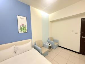 台中市にある台中住宿のベッドと椅子2脚があるホテルの部屋