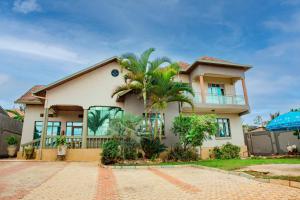 a house with a palm tree in front of it at THELIGHT SUITES KIGALI Rwanda in Kigali