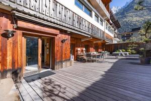 a wooden deck with tables and chairs on a building at Apartment Au Bon Coin - Luxury Chamonix Hidden Haven, Mont Blanc view, Hot Tub and Garden in Chamonix-Mont-Blanc
