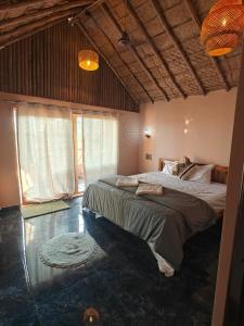 a bedroom with a large bed in a room with windows at The Sundown Hampi in New Hampi