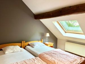 two beds in a bedroom with a skylight at Au petit Clocher - vakantiehuis Ardennen in Ferrières