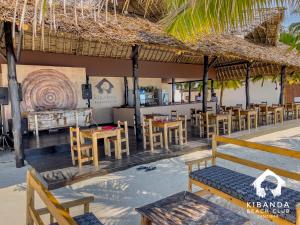 a restaurant with tables and chairs and a bench at Kibanda Natural Kendwa Villa in Kendwa