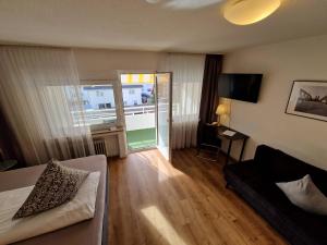 Una sala de estar con una cama, un sofá y un televisor. en Apart Hotel Freiburg, en Freiburg im Breisgau
