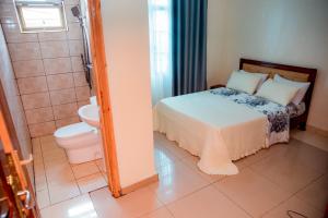 a bedroom with a bed and a shower and a toilet at THELIGHT SUITES KIGALI Rwanda in Kigali