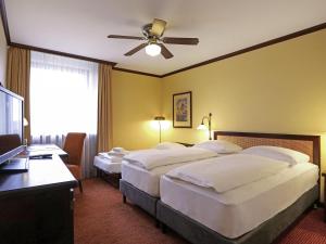 Una habitación de hotel con dos camas y un ventilador de techo. en Mercure Hotel Frankfurt Airport Langen, en Langen 119 fotos más