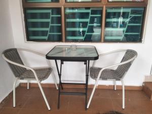 2 Stühle und ein Glastisch vor einem Fenster in der Unterkunft D'tasek Homestay Gua Musang in Gua Musang + 9 Fotos
