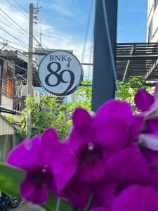 un cartel con flores púrpuras delante de un edificio en BNK89 Hostel, en Bangkok