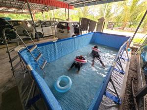 zwei Personen, die im Wasser in einem Pool spielen in der Unterkunft Dunia Kanak Kanak Homestay in Kota Bharu