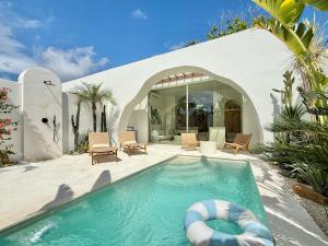 a swimming pool with a pool noodle in front of a house at Dolce Suites in Bingin Beach