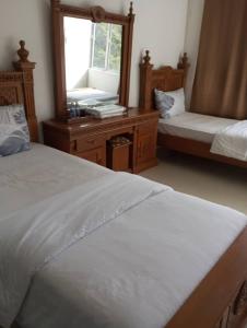 Un dormitorio con dos camas y un gran espejo. en Hotel Nusantara, en Jertih