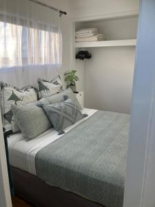 a bedroom with a bed with pillows and a window at Quiet,1 x Queen, Farm Stay Self-Contained unit in Empire Vale