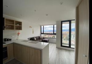a white kitchen with a view of a living room at Infinity Rooftop Pool Penthouse with 24h Gym, Near Zona T! in Bogotá