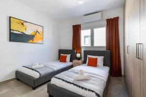 two beds in a room with orange curtains at Hilltop 2-Bedroom Apartment in Larnaca