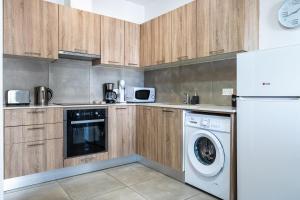 a kitchen with wooden cabinets and a washer and dryer at Hilltop 2-Bedroom Apartment in Larnaca