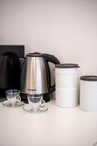 a coffee pot and two cups on a counter at LHE Les Trois Merveilles Rosé Charles in Cesena