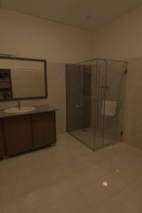 a bathroom with a glass shower and a sink at Clifton Business Hotel in Karachi