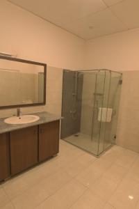 a bathroom with a glass shower and a sink at Clifton Business Hotel in Karachi