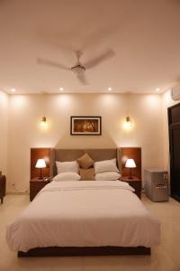 a bedroom with a large white bed with two lamps at Clifton Business Hotel in Karachi