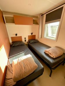 deux lits dans une petite pièce avec une fenêtre dans l'établissement La Yole Mobilhome Premium 6 pers avec terrasse lounge, à Vendres 38 autres photos
