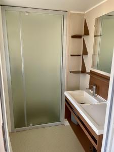 une salle de bain avec une douche en verre et un lavabo dans l'établissement La Yole Mobilhome Premium 6 pers avec terrasse lounge, à Vendres