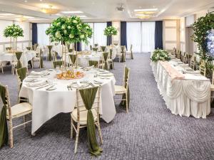 a banquet room with white tables and chairs with flowers at Mercure Nottingham Sherwood in Nottingham +108 photos