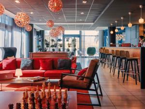 a living room with a red couch and a bar at Hôtel Mercure Toulon La Seyne-Sur-Mer in La Seyne-sur-Mer