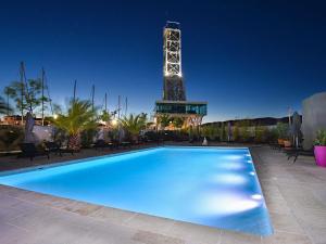 a large blue swimming pool with a tower in the background at Hôtel Mercure Toulon La Seyne-Sur-Mer in La Seyne-sur-Mer