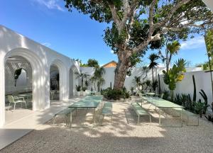 a patio with tables and chairs and a tree at Dolce Suites in Bingin Beach
