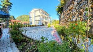 a large white house next to a stone wall at Shri Rudra's Service Apartments in Bhīm Tāl +1 photo